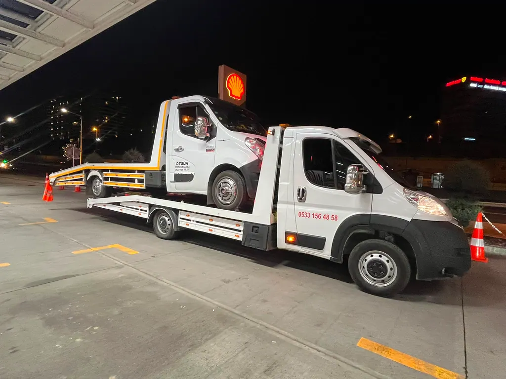 Akbulut Yol Yardım çekicisi gece benzin istasyonunda başka bir çekiciyi platformda taşırken