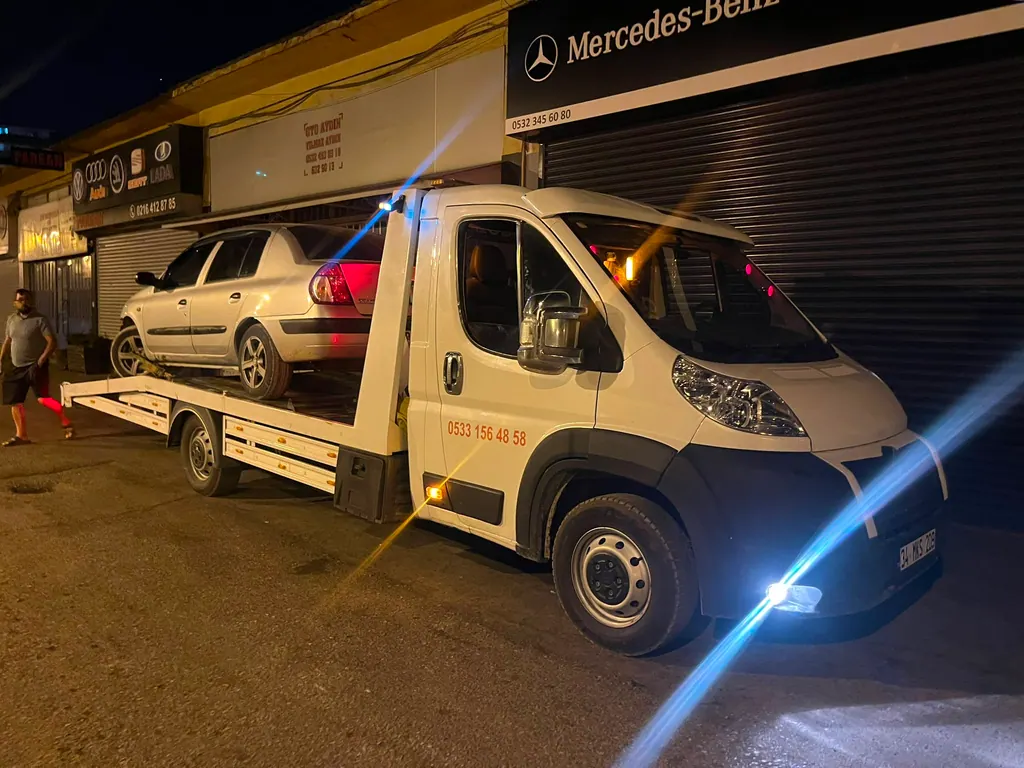 Akbulut Yol Yardım çekicisi gece bir oto servisin önünde arızalı otomobili indirirken