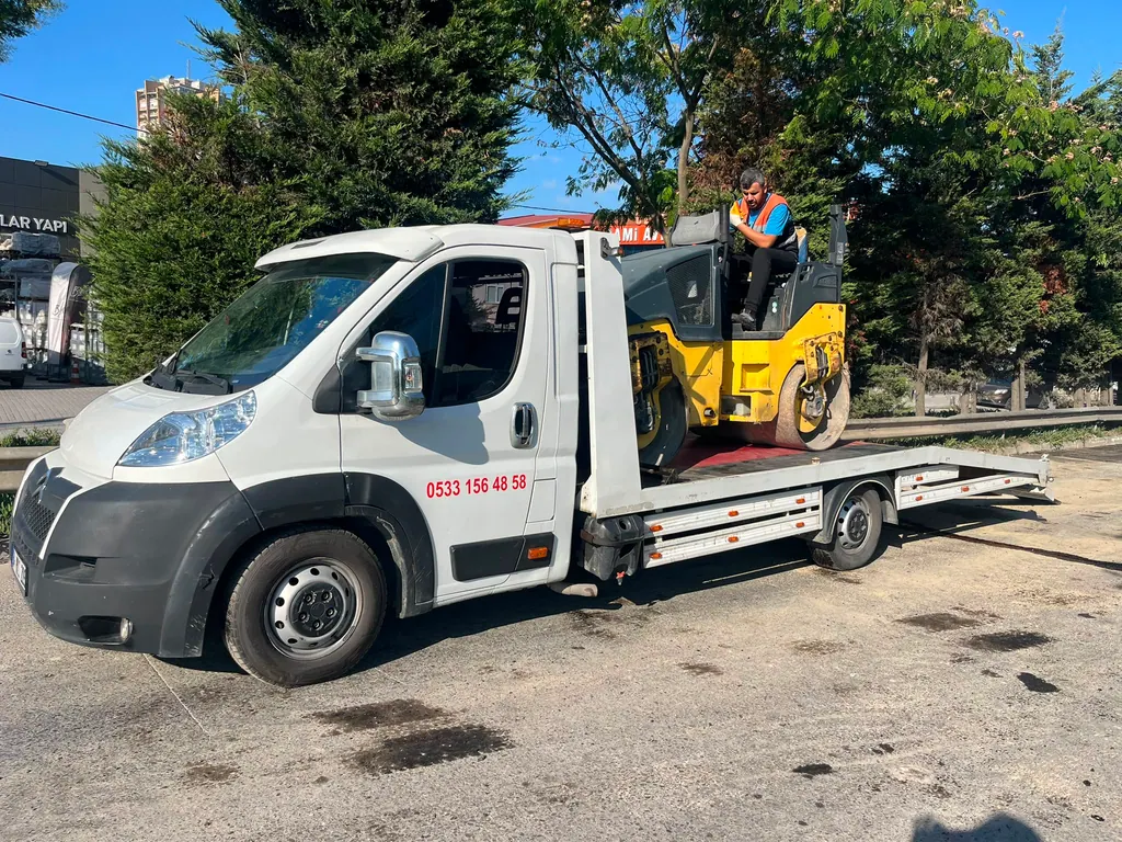 Akbulut Yol Yardım çekicisi üzerinde sarı bir yol silindiri taşırken, operatör silindirin üzerinde