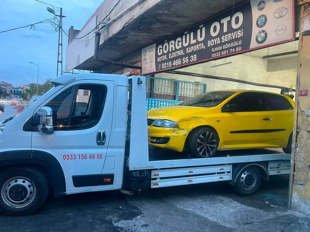 Akbulut Yol Yardım çekicisi kaza yapmış sarı bir otomobili kaporta servisine getirirken